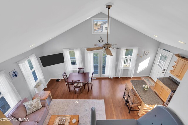 living room featuring high vaulted ceiling, baseboards, and wood finished floors