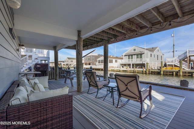 wooden terrace featuring stairs, outdoor lounge area, a residential view, and a water view