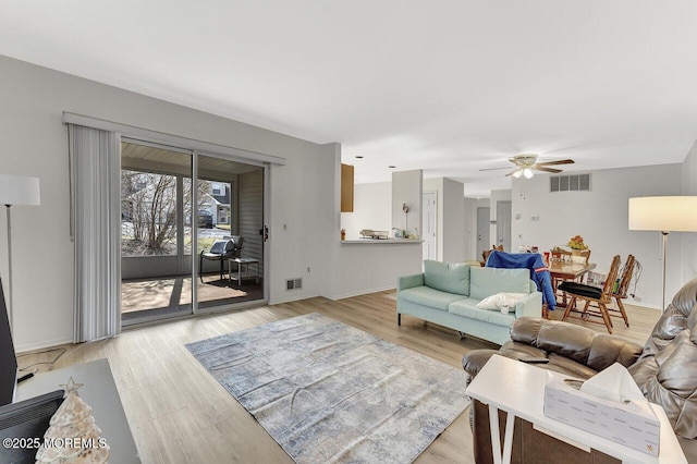 living area featuring a ceiling fan, visible vents, and light wood finished floors