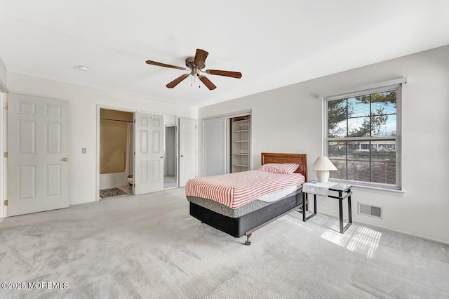 carpeted bedroom with a closet, visible vents, and ceiling fan