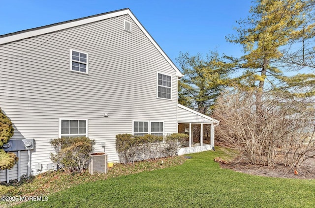 view of home's exterior featuring central air condition unit, a lawn, and a sunroom