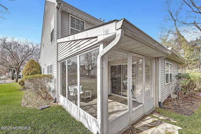 view of home's exterior with a lawn and a sunroom