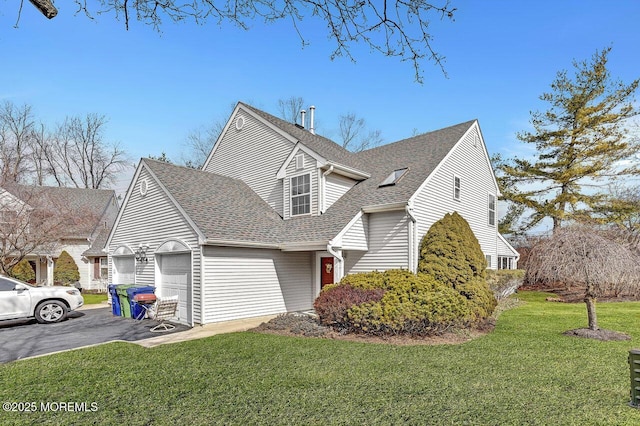 view of front of home featuring aphalt driveway, an attached garage, a shingled roof, and a front yard