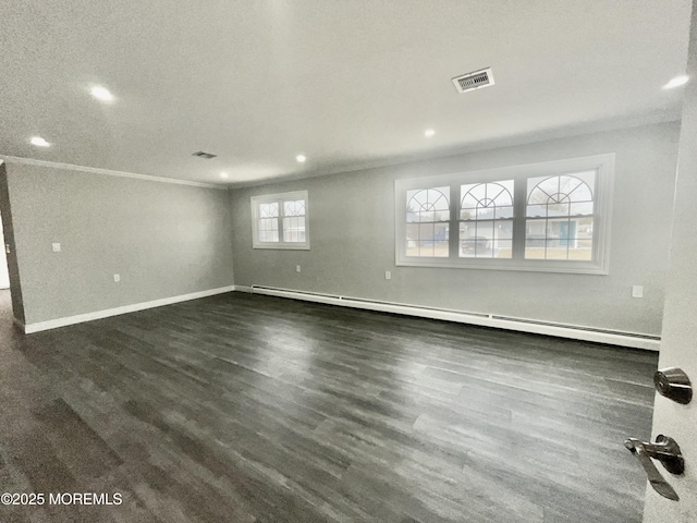 spare room featuring visible vents, dark wood-type flooring, baseboards, crown molding, and baseboard heating