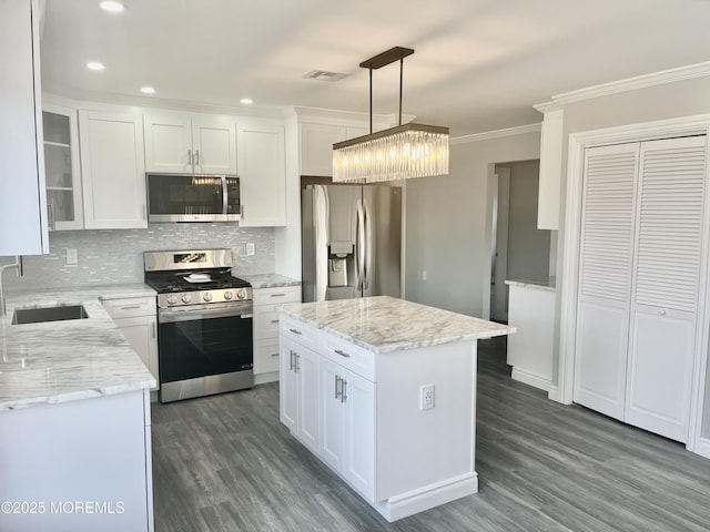 kitchen with visible vents, a sink, ornamental molding, stainless steel appliances, and white cabinets