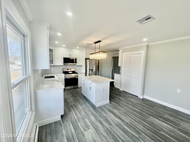 kitchen with visible vents, ornamental molding, a sink, stainless steel appliances, and decorative backsplash