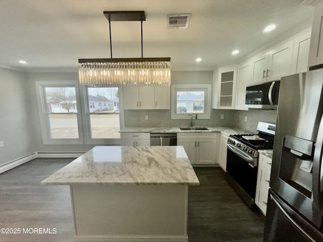 kitchen with light stone counters, decorative backsplash, appliances with stainless steel finishes, white cabinetry, and a sink