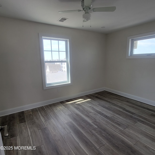 unfurnished room featuring visible vents, dark wood-style flooring, ceiling fan, and baseboards