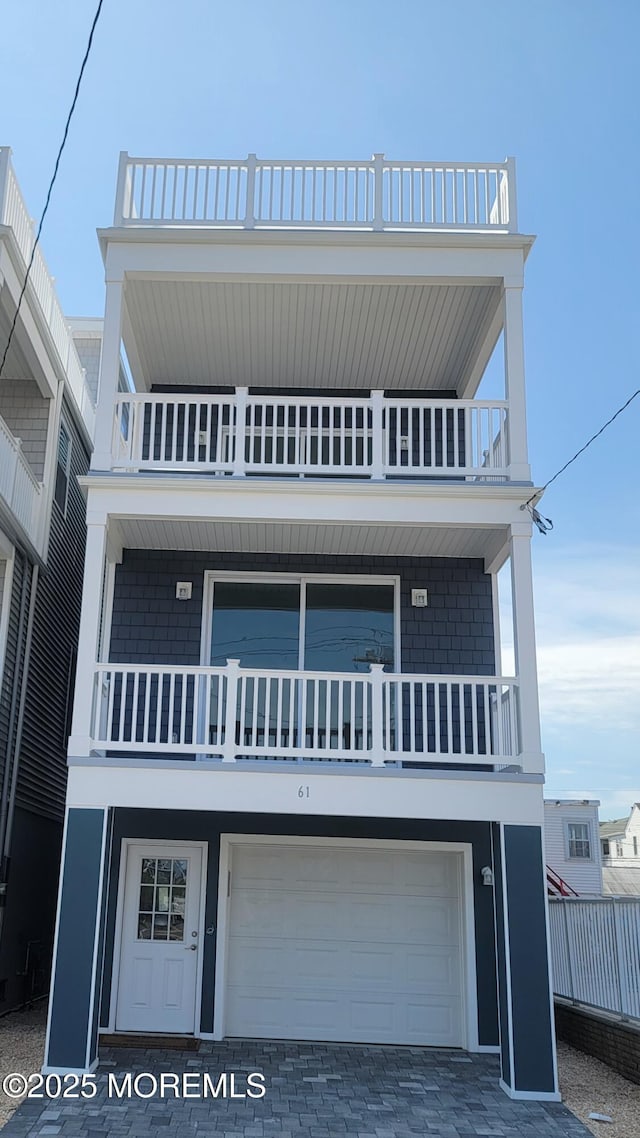 raised beach house with an attached garage, a balcony, and driveway