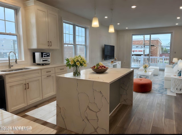 kitchen with light wood-style floors, a sink, light stone counters, and a wealth of natural light
