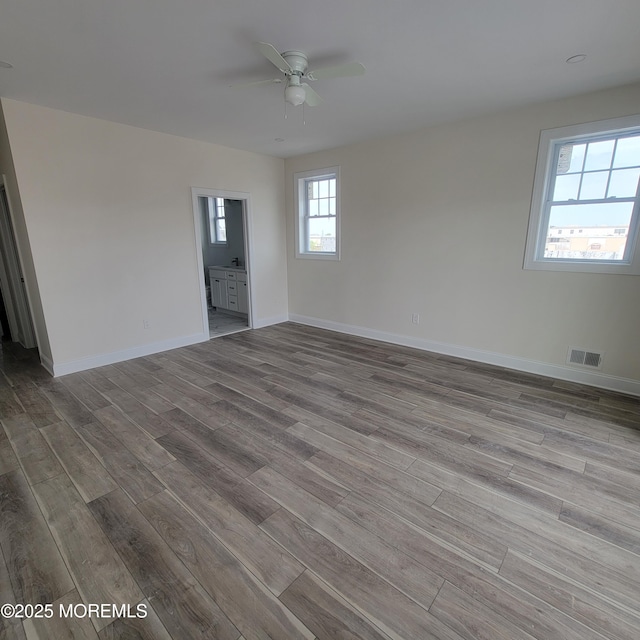 empty room featuring baseboards, ceiling fan, wood finished floors, and visible vents