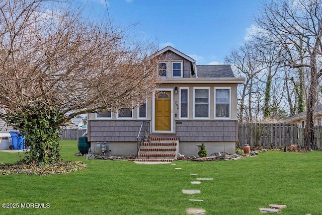 bungalow-style house with entry steps, a front lawn, and fence