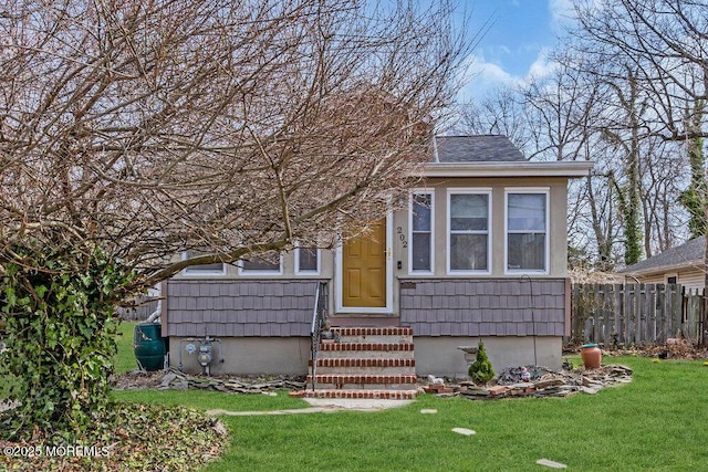 view of front of house featuring entry steps, a front lawn, and fence