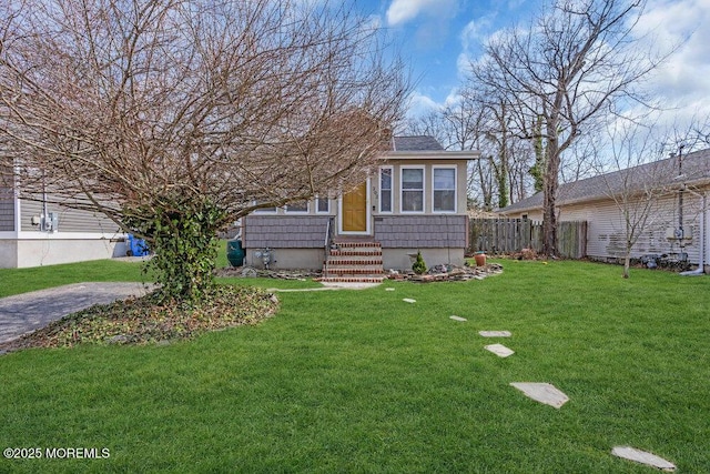 view of front of home featuring entry steps, a front lawn, and fence