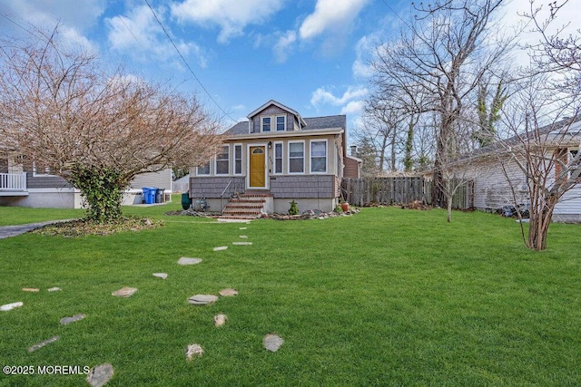 view of front of home with entry steps, a front lawn, and fence