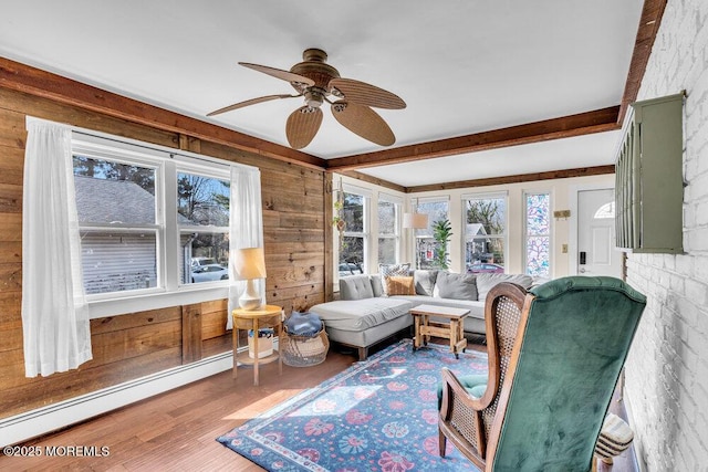 sunroom / solarium featuring beamed ceiling, a baseboard heating unit, and a ceiling fan