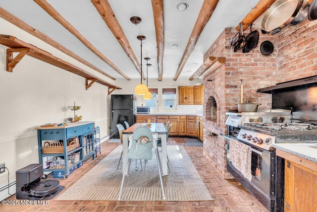 kitchen with beamed ceiling, decorative light fixtures, appliances with stainless steel finishes, light countertops, and brick floor