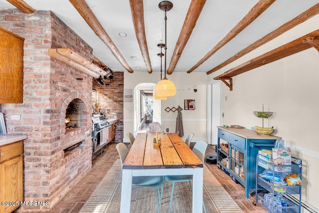 dining space featuring brick floor, arched walkways, and beam ceiling