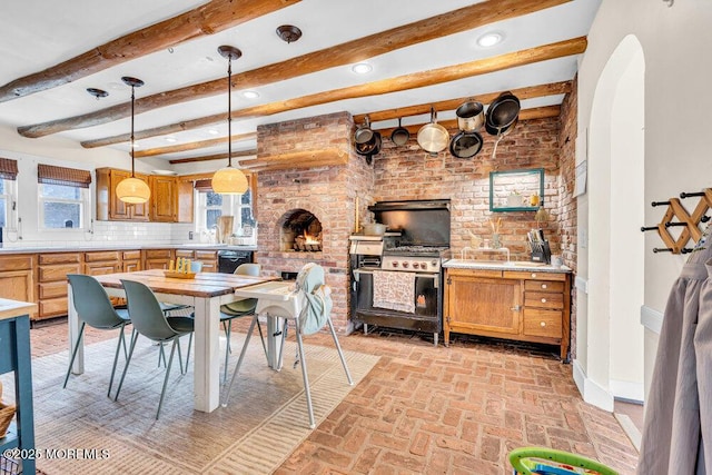 dining room with arched walkways, beam ceiling, baseboards, and brick floor