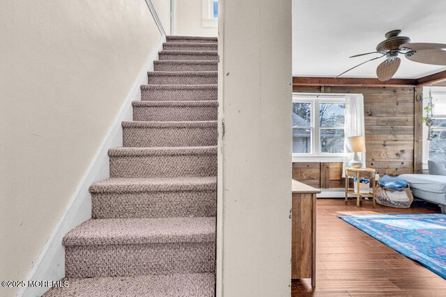 stairway with wood finished floors, a baseboard radiator, and ceiling fan