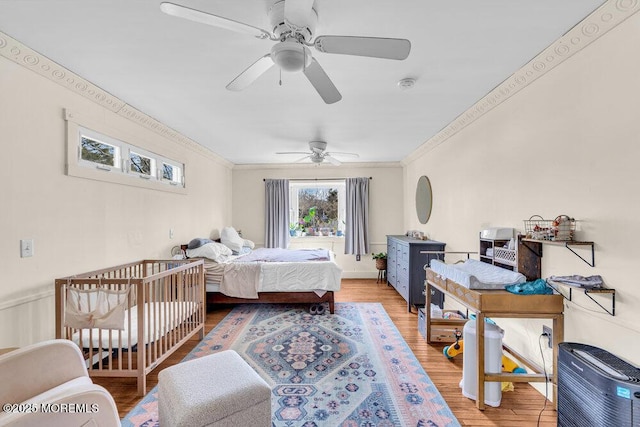 bedroom featuring crown molding, light wood-type flooring, and ceiling fan