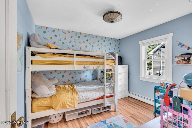 bedroom with a baseboard heating unit and wood finished floors