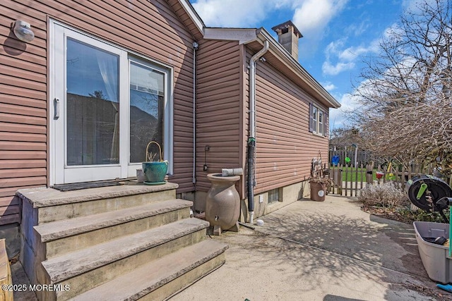 entrance to property featuring a chimney, a patio, and fence