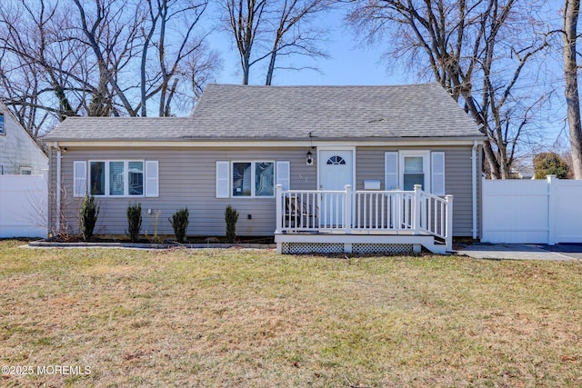 view of front of home featuring a front lawn, fence, and roof with shingles