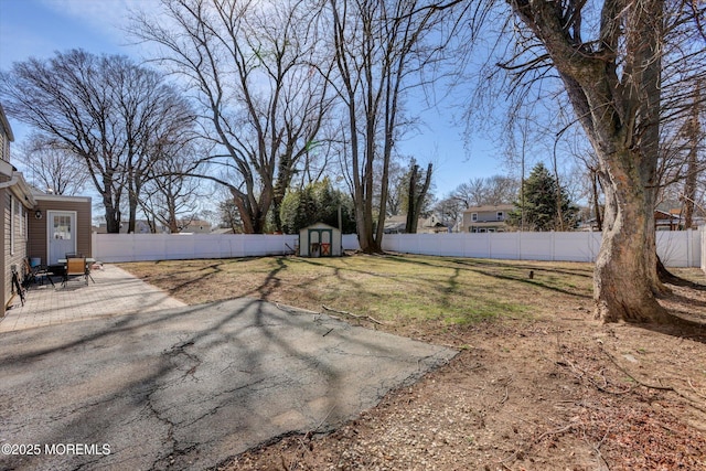 view of yard with a fenced backyard, an outbuilding, a storage shed, and a patio area