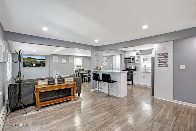 living room featuring recessed lighting, light wood-type flooring, and baseboards