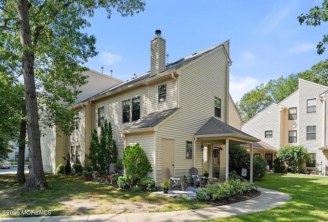 rear view of house featuring a yard, a patio area, and a chimney