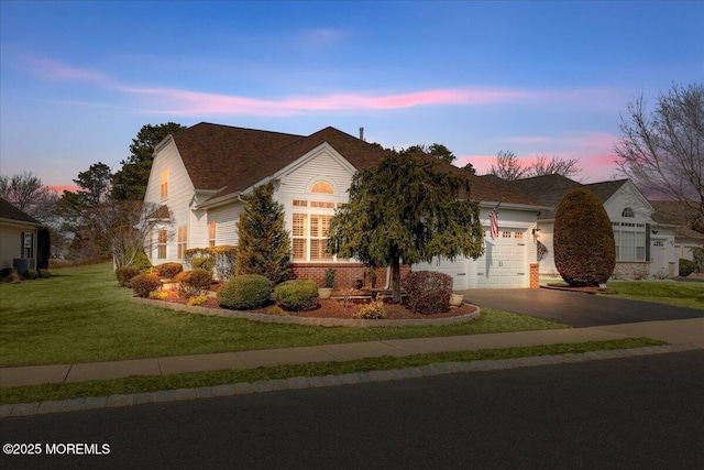 view of front of home with a yard, driveway, brick siding, and a garage