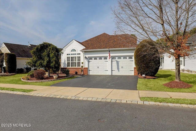 view of front of house featuring brick siding, driveway, an attached garage, and a front lawn