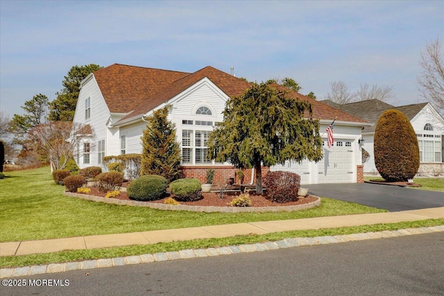 view of front of property with aphalt driveway, an attached garage, brick siding, and a front lawn