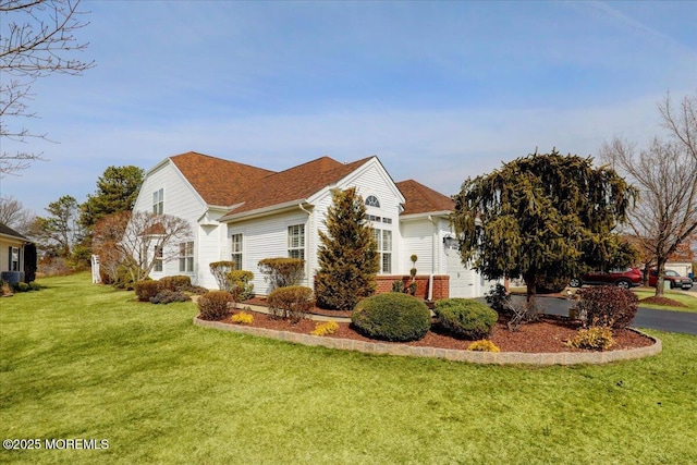 view of side of home featuring a yard, brick siding, and an attached garage