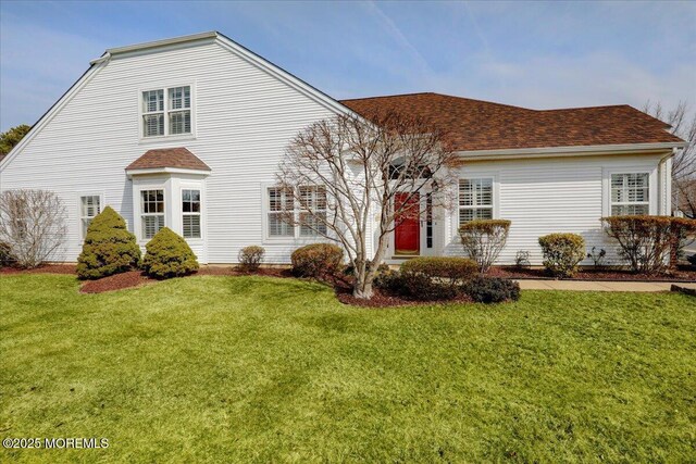 view of front of property featuring a front yard and a shingled roof