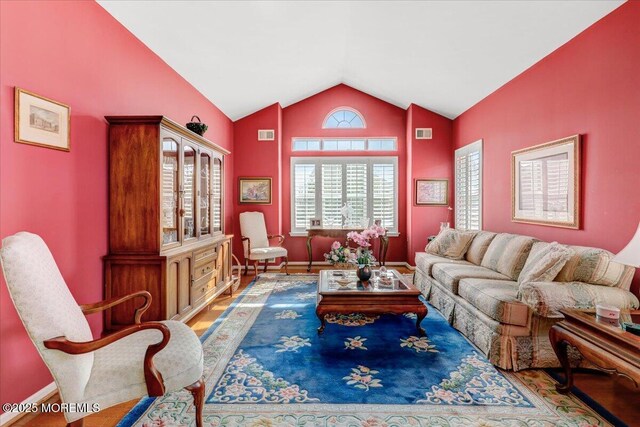 living area featuring vaulted ceiling, wood finished floors, baseboards, and visible vents