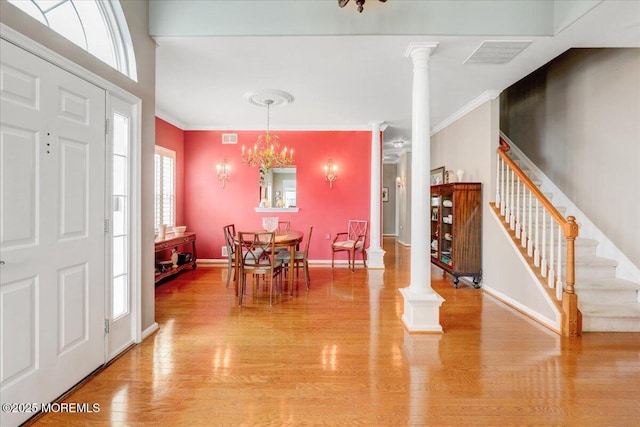 entrance foyer with visible vents, ornamental molding, light wood-style floors, stairs, and ornate columns