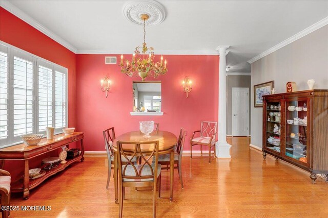 dining room featuring visible vents, ornamental molding, decorative columns, light wood-style floors, and a notable chandelier