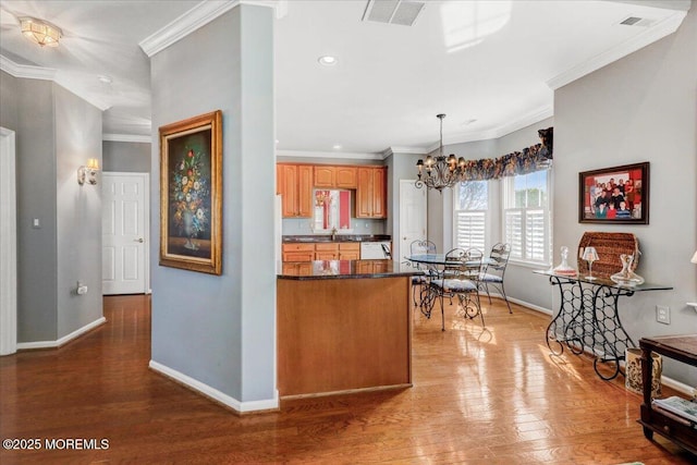 kitchen with dark countertops, visible vents, dishwasher, ornamental molding, and wood finished floors