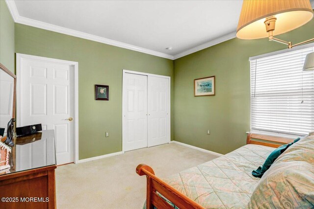 carpeted bedroom with a closet, baseboards, and ornamental molding