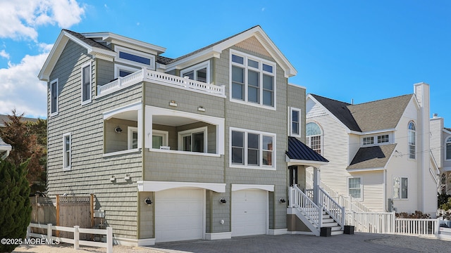 view of front of property featuring a garage, decorative driveway, a balcony, and fence