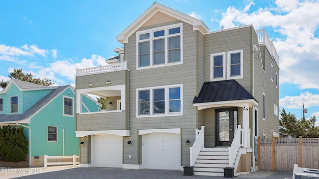 view of front of home featuring a balcony, fence, a standing seam roof, decorative driveway, and metal roof