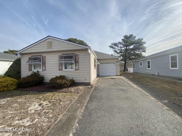 view of front of property featuring aphalt driveway, an outbuilding, and a garage