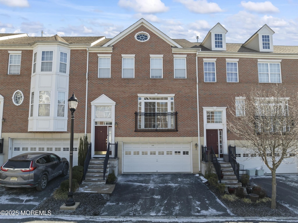 townhome / multi-family property with brick siding, a garage, and driveway