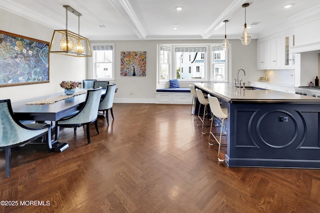 kitchen featuring a kitchen island with sink, white cabinets, crown molding, and a sink