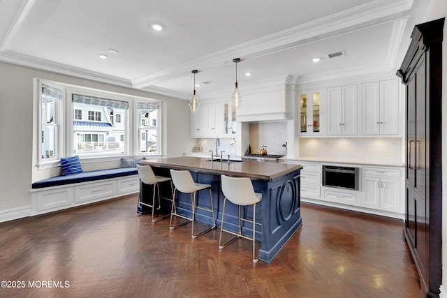 kitchen featuring a sink, glass insert cabinets, a kitchen bar, and white cabinetry