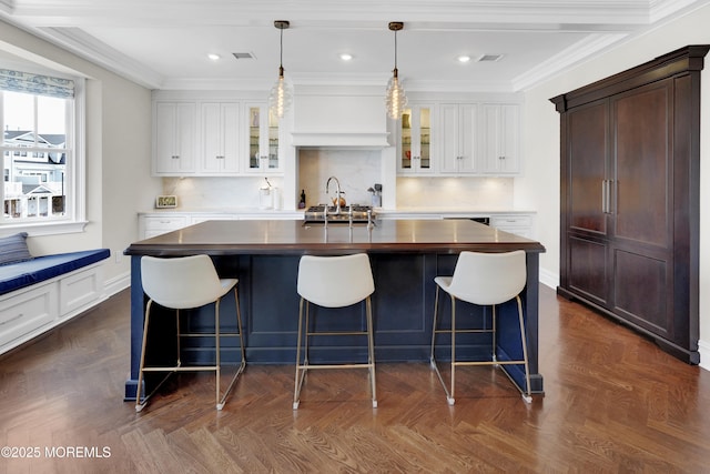 kitchen with dark countertops, visible vents, backsplash, glass insert cabinets, and crown molding