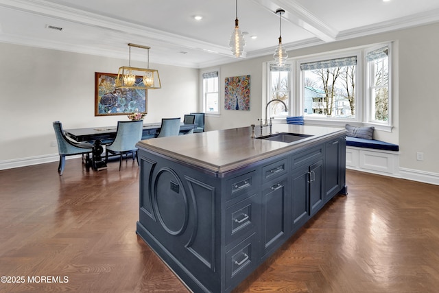 kitchen featuring visible vents, a sink, blue cabinetry, dark countertops, and baseboards