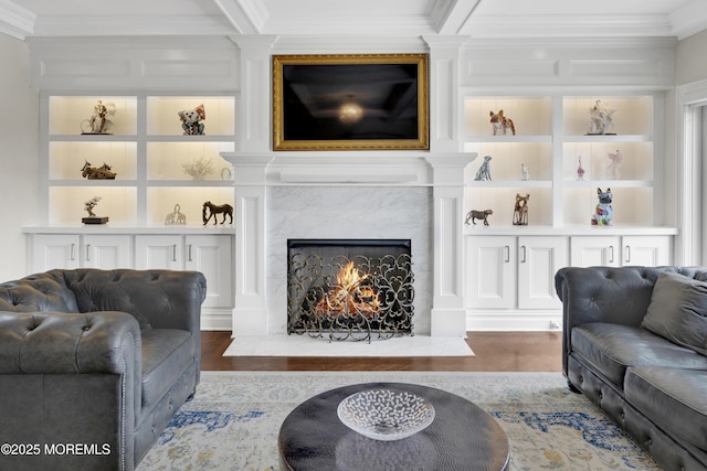 living room with a high end fireplace, built in features, wood finished floors, and ornamental molding